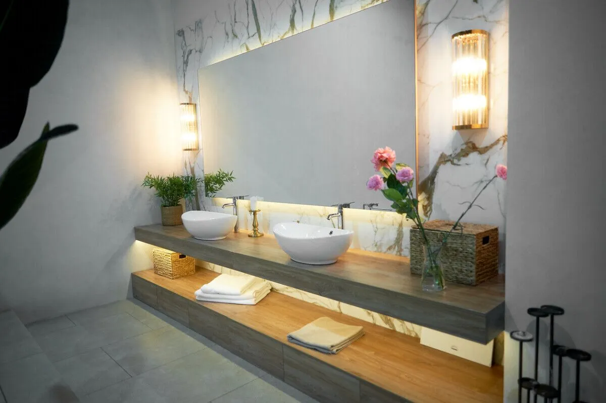 Bathroom with large mirror, two sinks and flowers