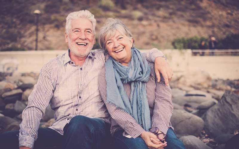 A happy elder couple laughing on a bench