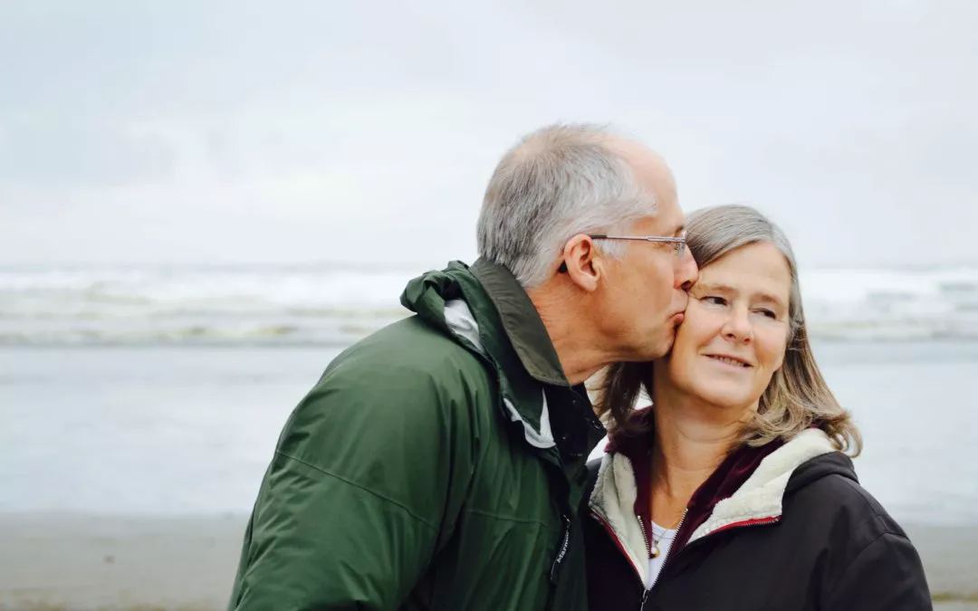 An elder couple kissing at the sea