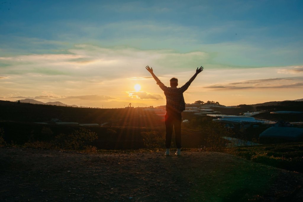 man with arms open at the top of a hill