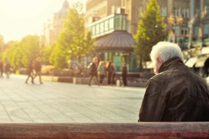 Elderly man sitting alone on a bench 