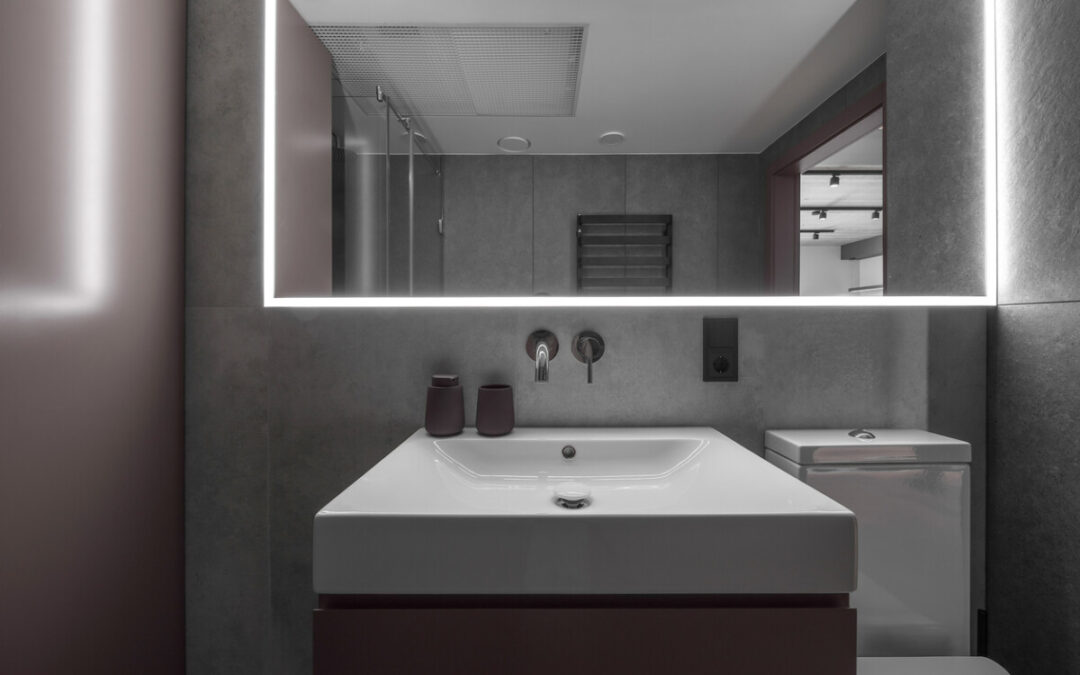 Modern minimalist bathroom interior design with grey stone tiles and over mirror lighting