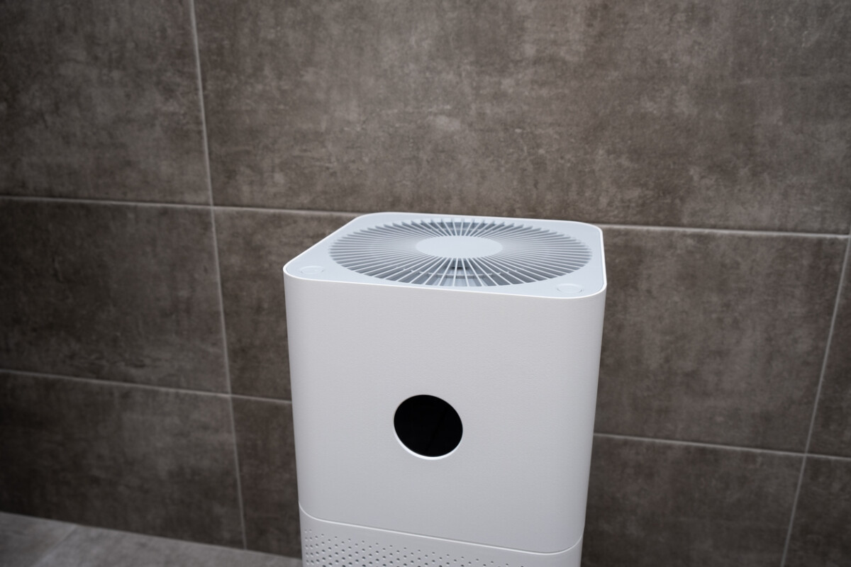 Close-up of a white indoor air purifier, designed to clean dust and allergens, placed in a modern home setting.
