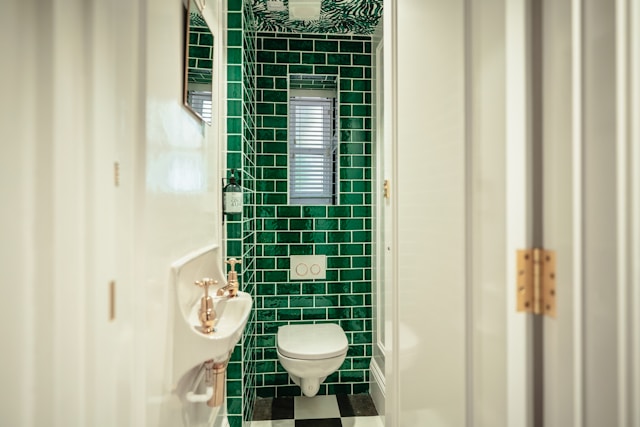 An image of a bathroom with a dark green tile feature wall