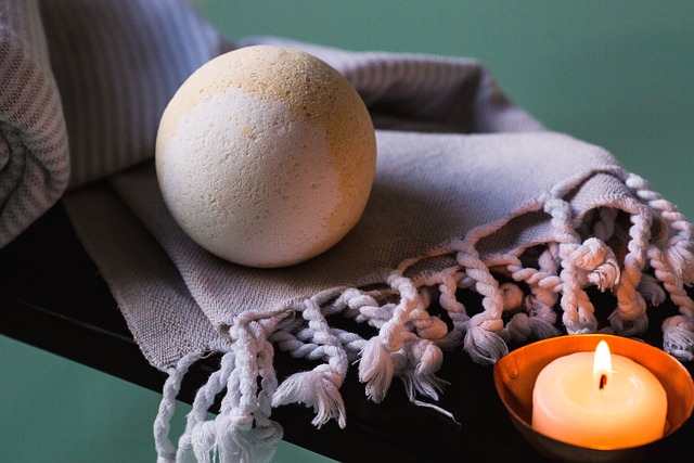 An image of a bath bomb folded on a towel next to a candle
