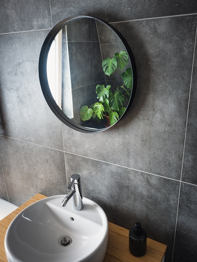 An image of a mirror and sink in a dark grey bathroom